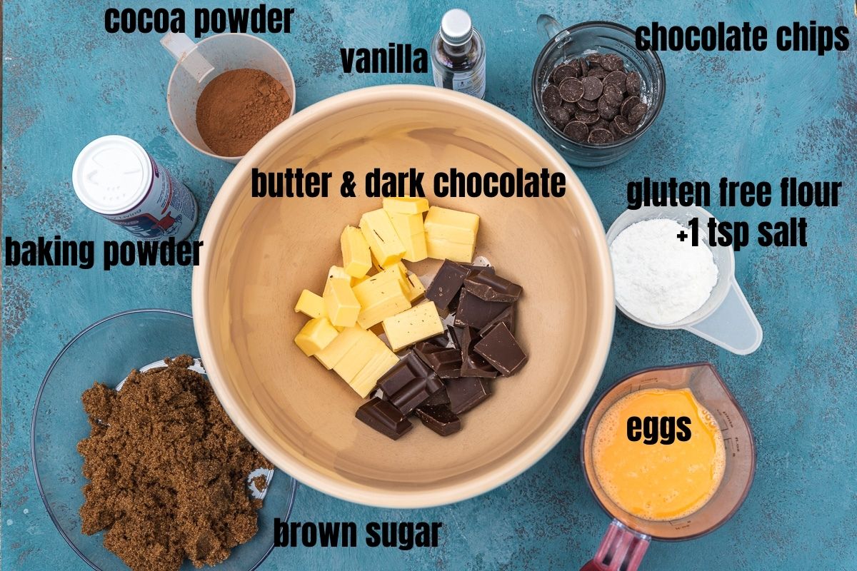 Overhead photo of the ingredients in gluten-free brownies including butter & dark chocolate, brown sugar, cocoa powder, baking powder, vanilla, chocolate chips, gluten-free flour and eggs