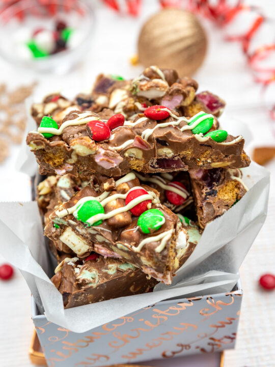 Christmas rocky road in a white and gold box with Christmas decorations behind