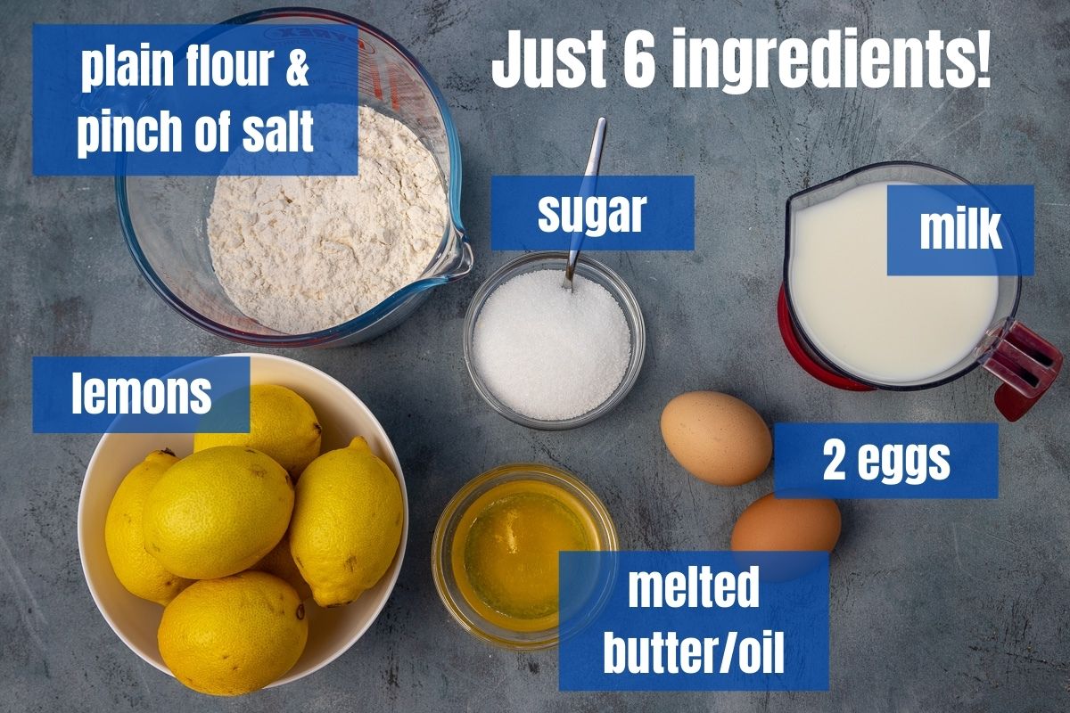 All 6 ingredients needed to make English pancakes with sugar and lemon labelled on a blue background