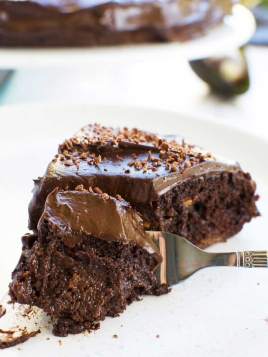 Closeup of a fork scooping up a piece of gooey healthy chocolate cake on a white plate