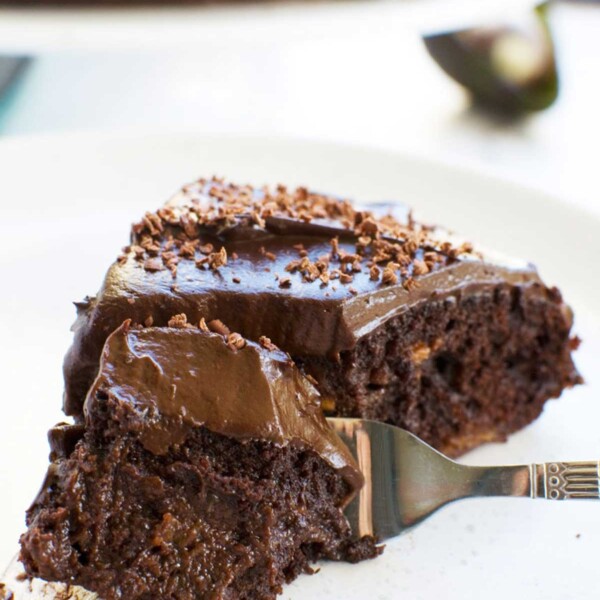 Closeup of a fork scooping up a piece of gooey healthy chocolate cake on a white plate