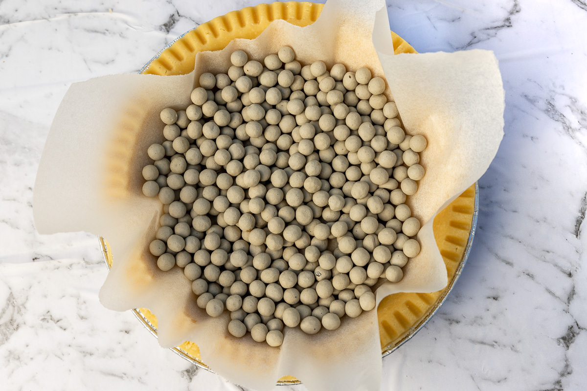 Pastry case lined with baking paper and baking beans ready to be blind baked.