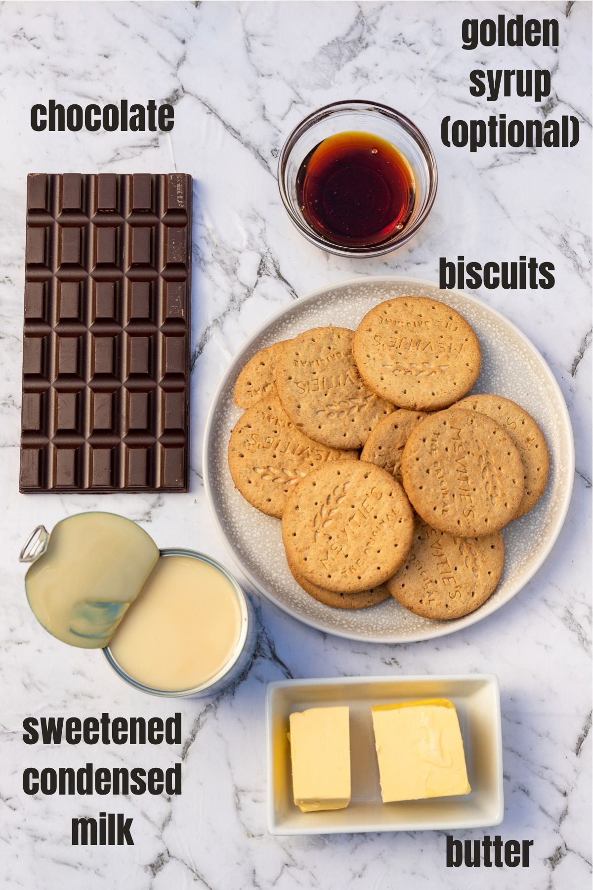 All the ingredients for caramel slice on a marble background and labelled including butter, sweetened condensed milk, golden syrup, chocolate, and biscuits