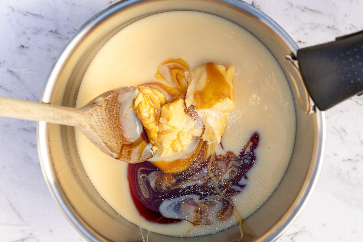 The 3 ingredients for the caramel for caramel slice in a saucepan from above with a wooden spoon