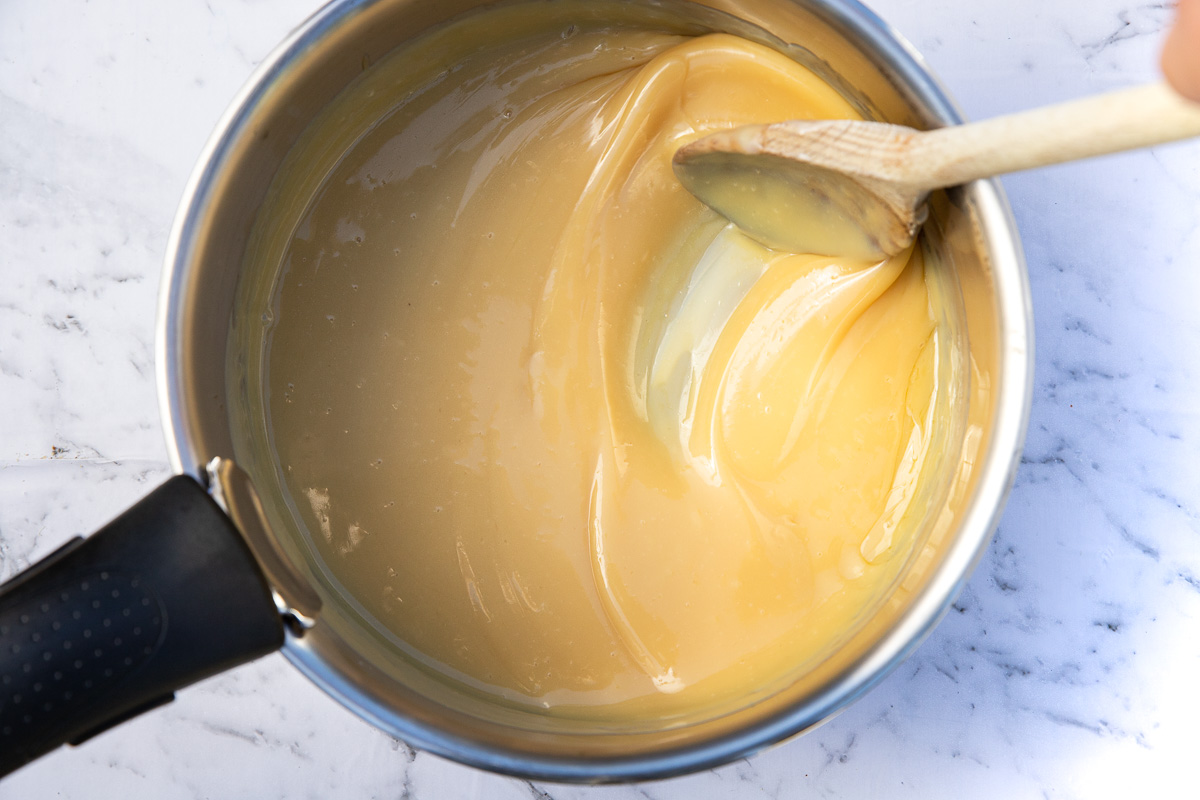 Someone stirring the caramel for a caramel slice in a saucepan from above