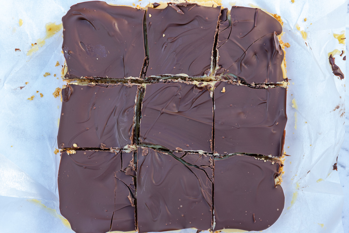 Squares of caramel slice that have just been sliced on baking paper from above