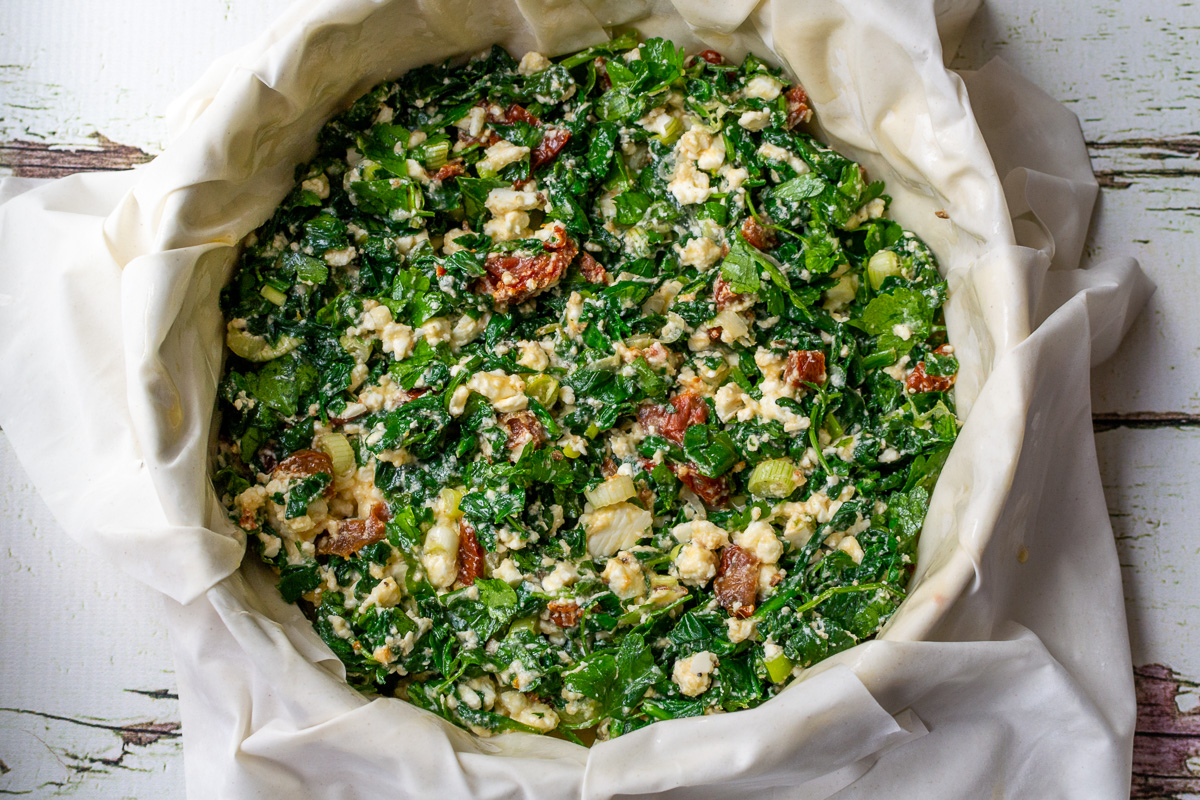 Overhead view of spinach feta filling in a filo pastry case ready to be assembled and baked.