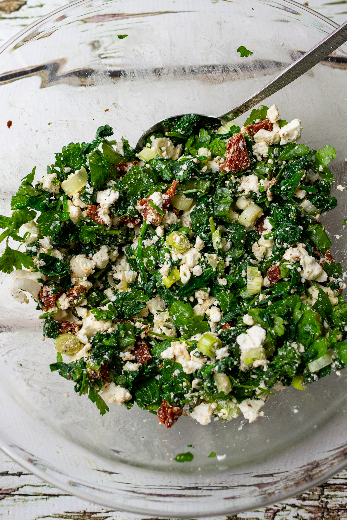 Overhead view of spinach and feta filling in a big glass bowl ready to go in a Greek filo pie.