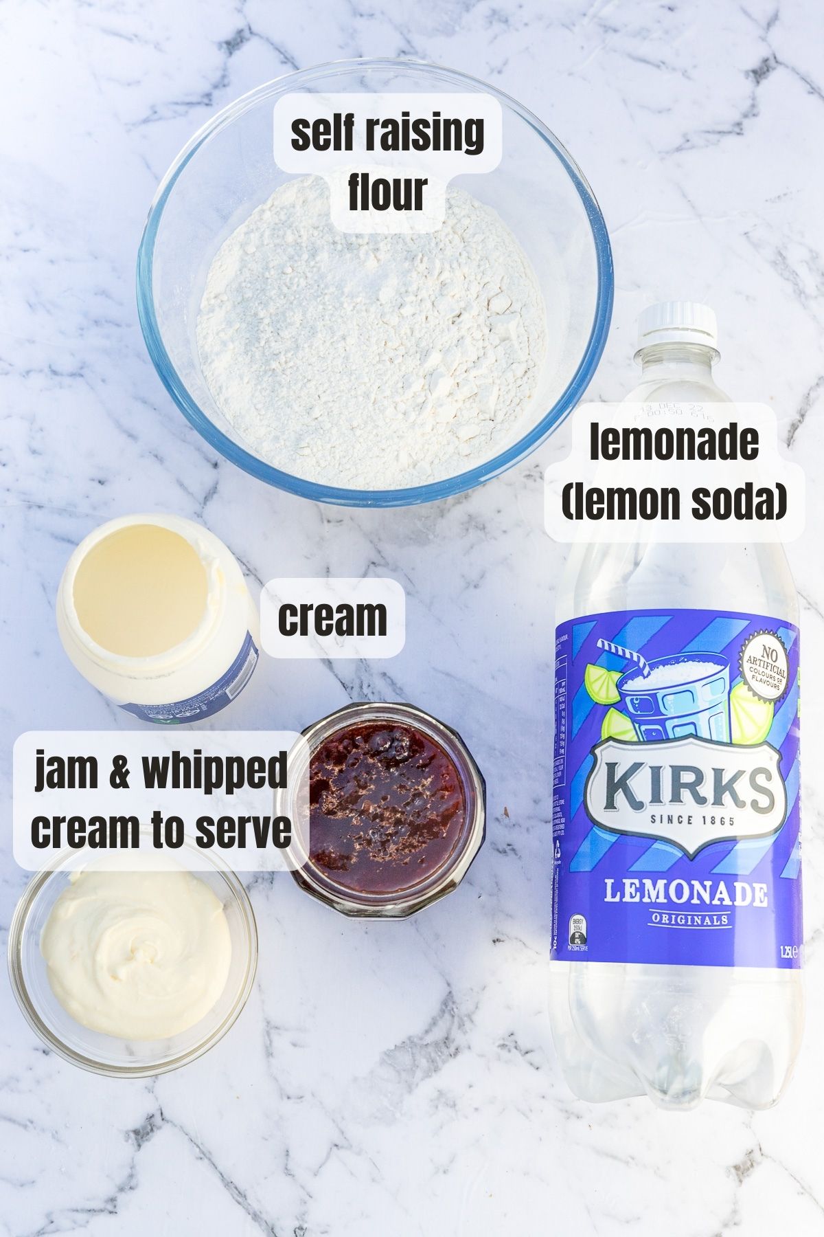 Lemonade scone ingredients labelled on a marbled background including self raising flour, cream, a bottle of lemonade and jam and cream for serving.