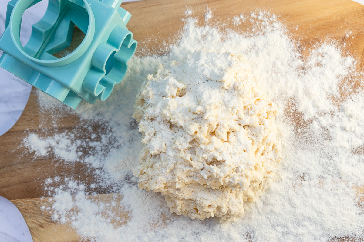 The dough for lemonade scones with flour on a wooden board from above.