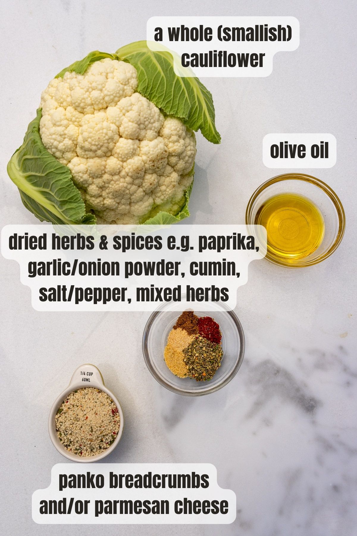 All the ingredients needed for air fryer cauliflower including a head of cauliflower, a mix of herbs and spices, olive oil and panko crumbs and parmesan, all on a marble background.