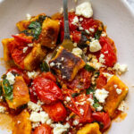 A closeup of an overhead view of a dish of pan-fried gnocchi in cherry tomato basil sauce with feta cheese sprinkled on top.