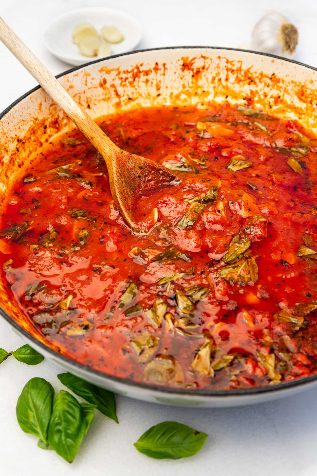 Closeup of a pan of homemade Italian marinara sauce with wooden spoon.