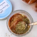 Overhead shot of all-purpose seasoning in an ornate glass jar with labelled lid at the side.