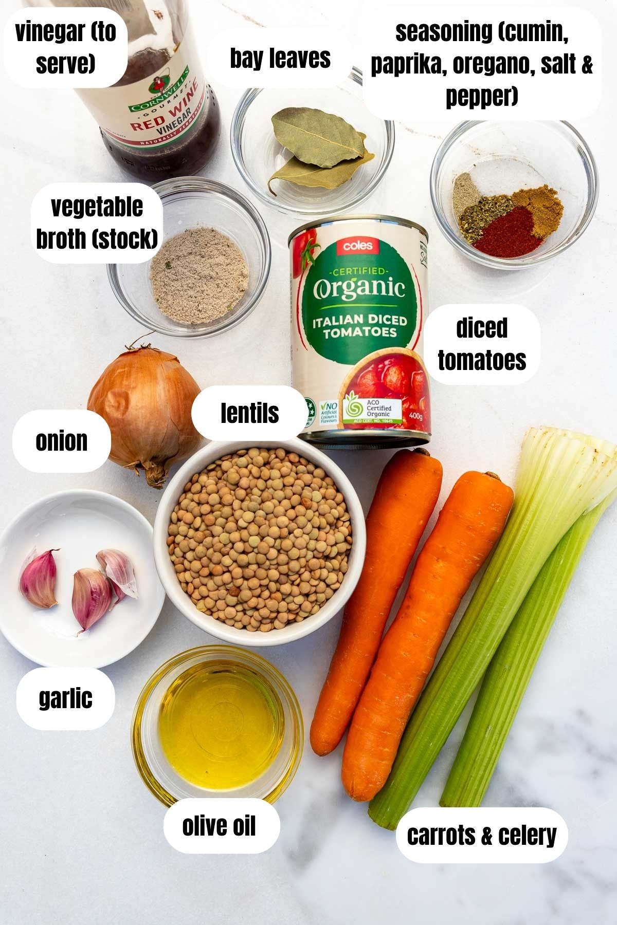 All labelled ingredients for Greek lentil soup including lentils, olive oil, carrots and celery, garlic, seasoning, bay leaves, broth, garlic, diced tomatoes and vinegar to serve.