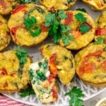 An overhead view of a plate of spinach egg muffins with one cut in half to shoe the inside.