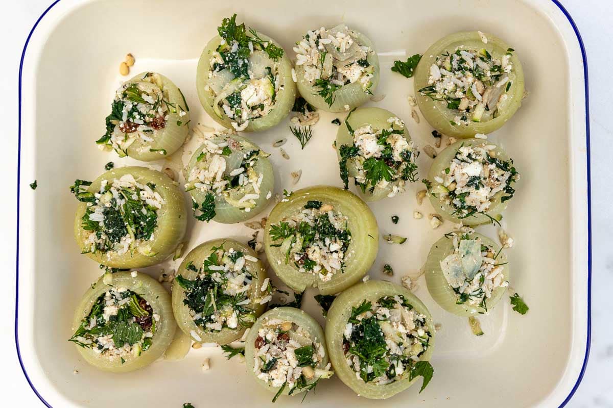 A pan of Mediterranean style stuffed onions shown from above in a white pan with blue rim.