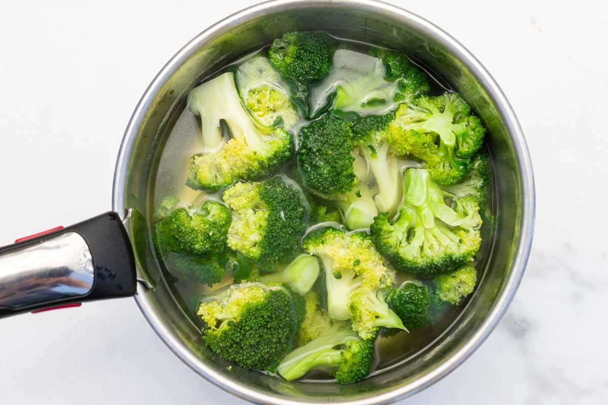 Par-boiled broccoli florets in a big pan of boiling water.
