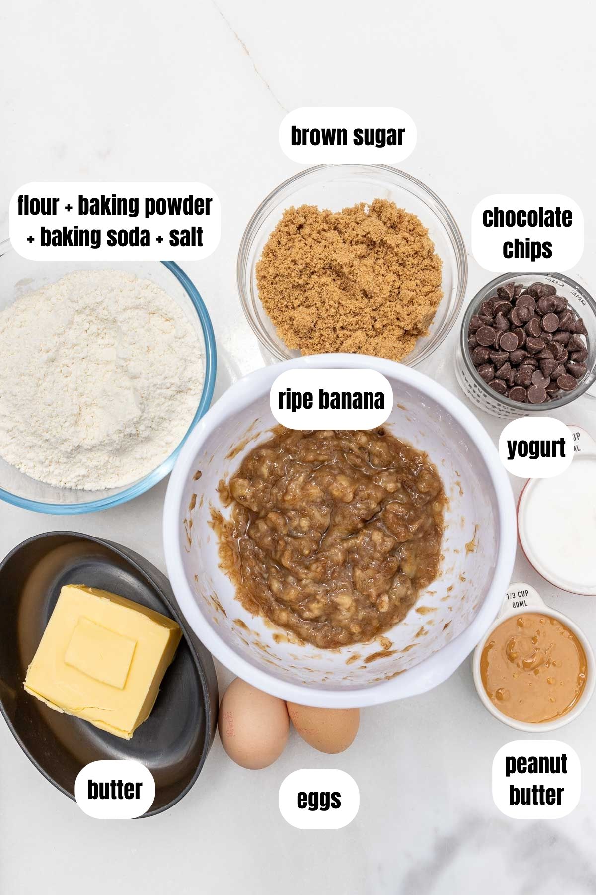 A collage of all the ingredients needed to make a peanut butter banana and chocolate cake including all-purpose flour, baking powder, baking soda and salt, brown sugar, butter, eggs, peanut butter, yogurt, mashed ripe banana and chocolate chips.