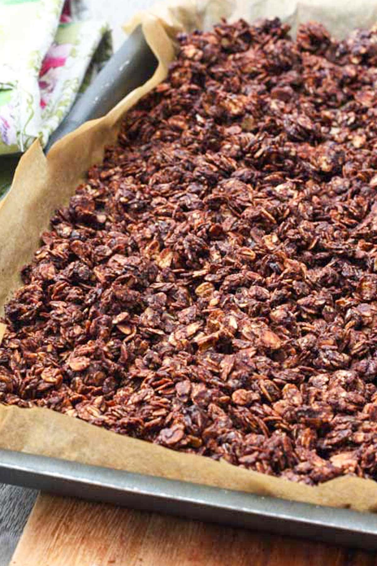 Closeup of crunchy dark chocolate granola just baked on a baking sheet.