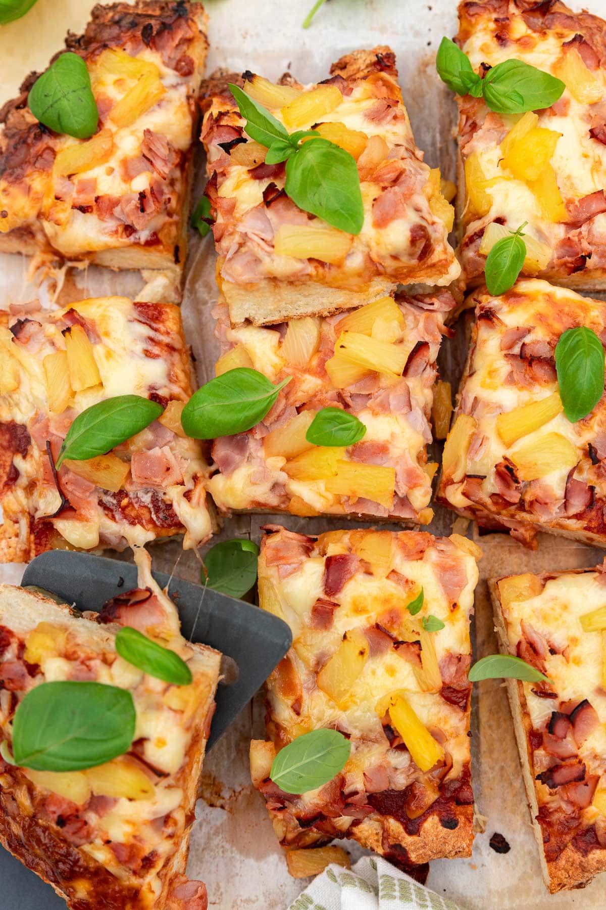 An overhead view of sheet pan Greek yogurt pizza sliced into rectangles, with fresh basil on top.