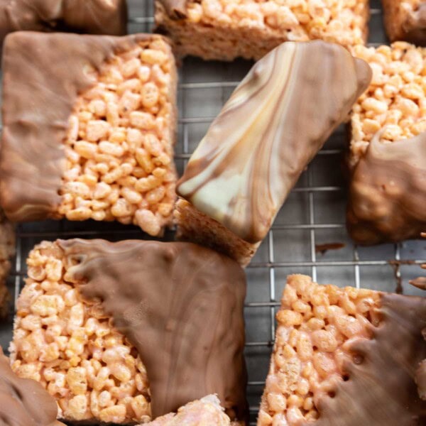 Overhead view of square rice krispie bars half dipped in swirled white and milk chocolate, all on a cooking rack.