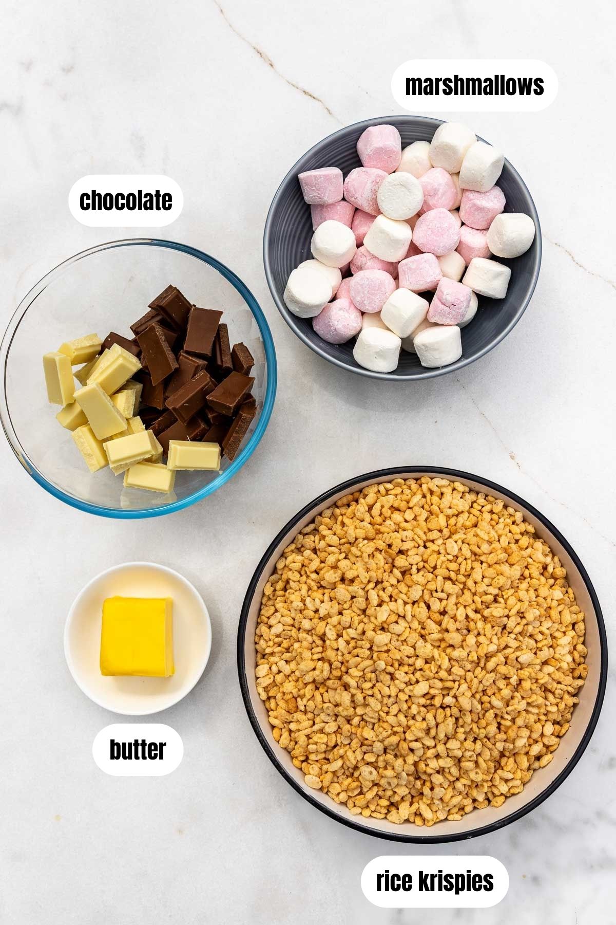 Overhead view of all the ingredients needed to make them including rice krispies, butter, marshmallows and white and milk chocolate.
