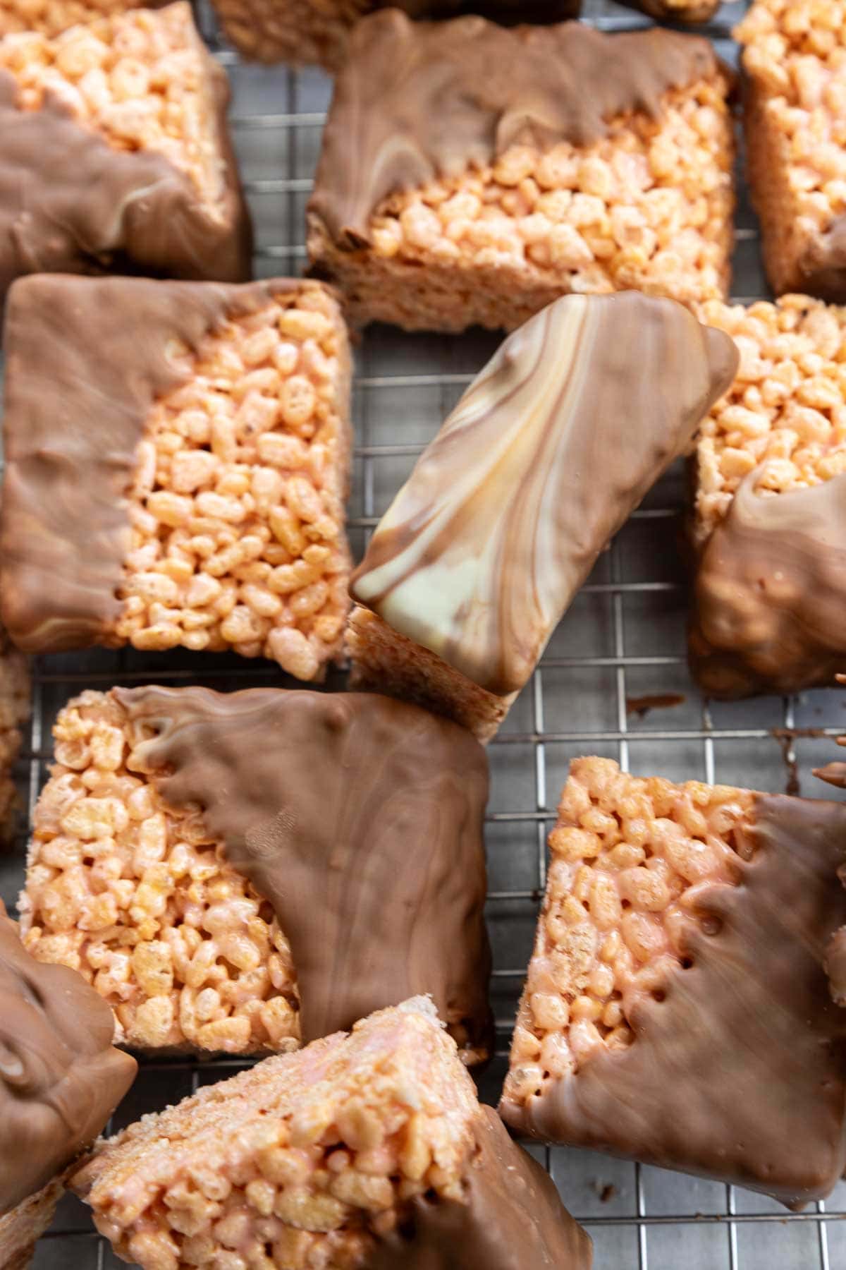 Overhead view of chocolate covered rice krispie bars half dipped in swirled white and milk chocolate, all on a cooking rack.