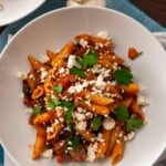Overhead of eggplant and ground beef pasta with feta and parsley on top, in a white dish.