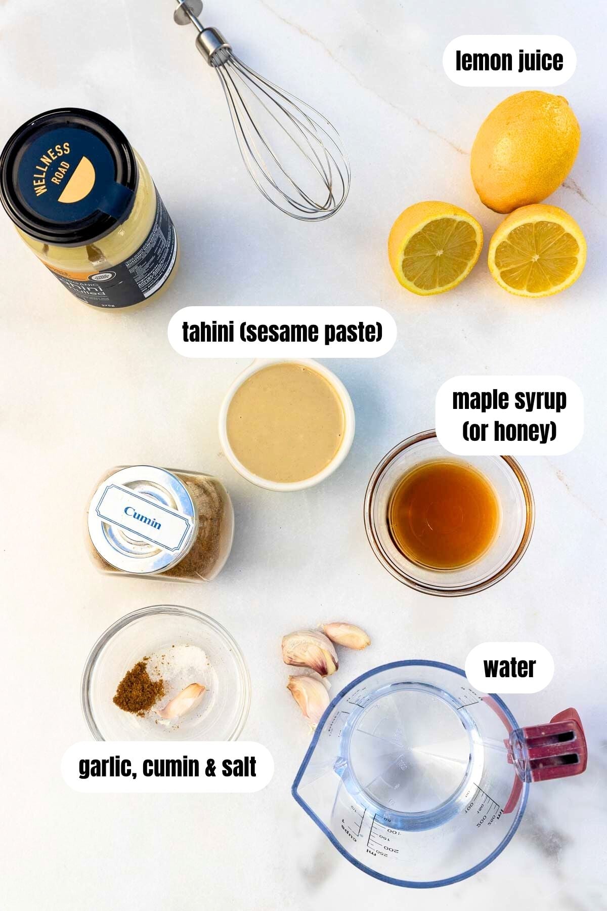All the ingredients needed to make the dressing including tahini, lemons, garlic, cumin, salt, maple syrup and water.