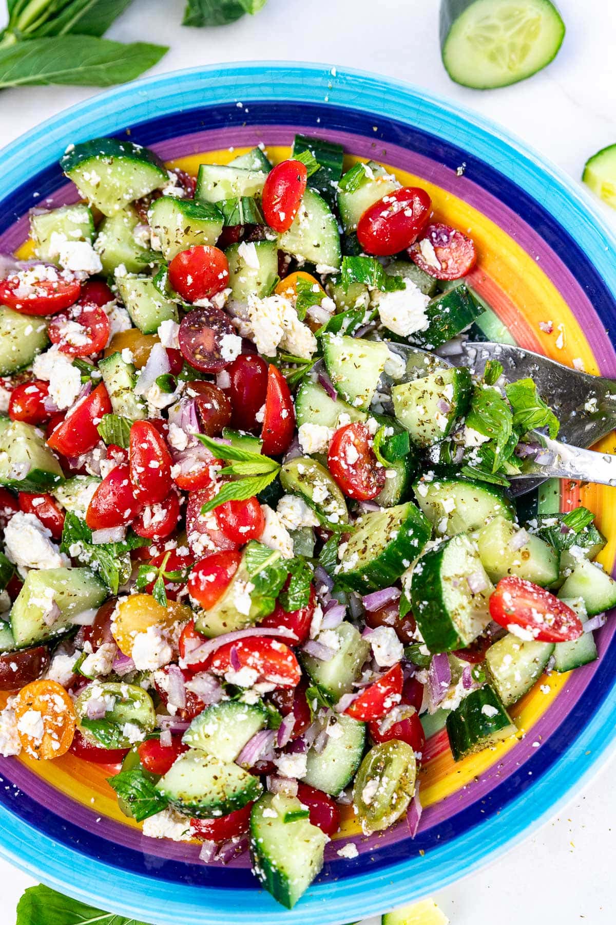 Closeup overhead of a colorful bowl of the salad, with salad servers in it.
