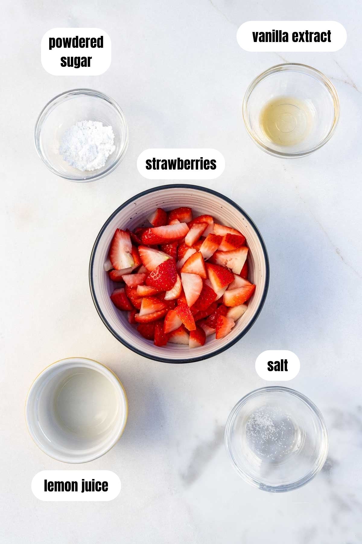 Overhead of all the ingredients to make a strawberry puree, including strawberries, lemon juice, powdered sugar, vanilla and salt.