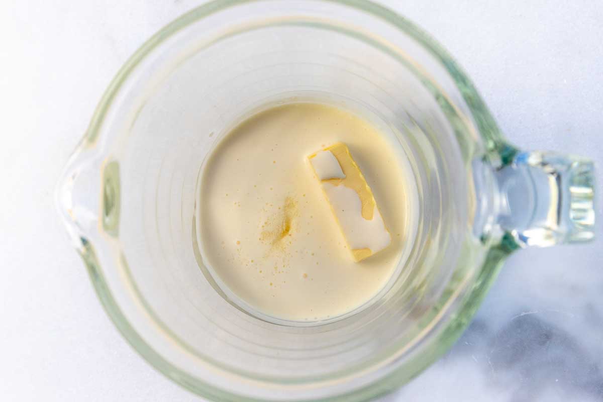 Overhead view of cream and butter in a glass jug.