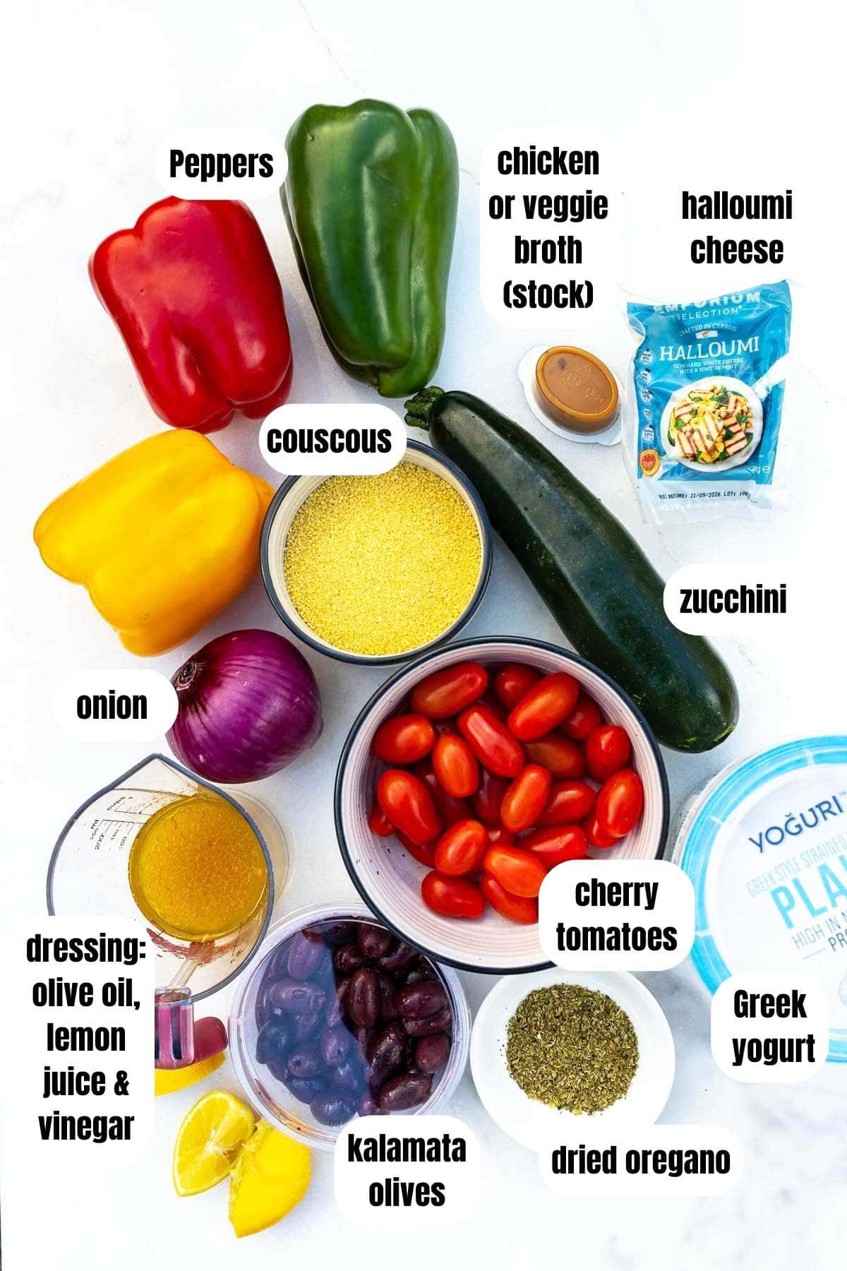 All ingredients needed to make vegetable couscous including couscous, colorful peppers, a simple dressing, kalamata olives, dried oregano, Greek yogurt to serve, cherry tomatoes, a zucchini, chicken or veggie broth and halloumi.