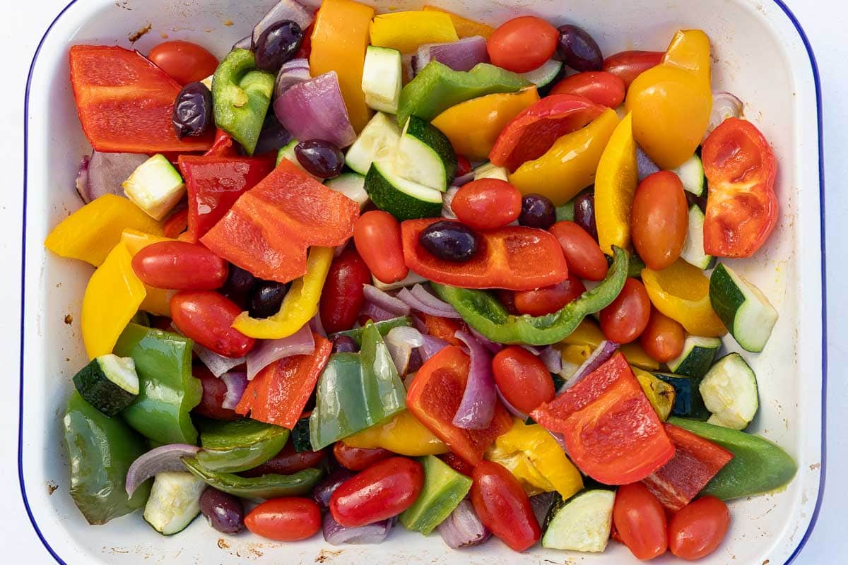 Chopped Mediterranean style vegetables and olives in a rectangular baking pan, ready to roast.