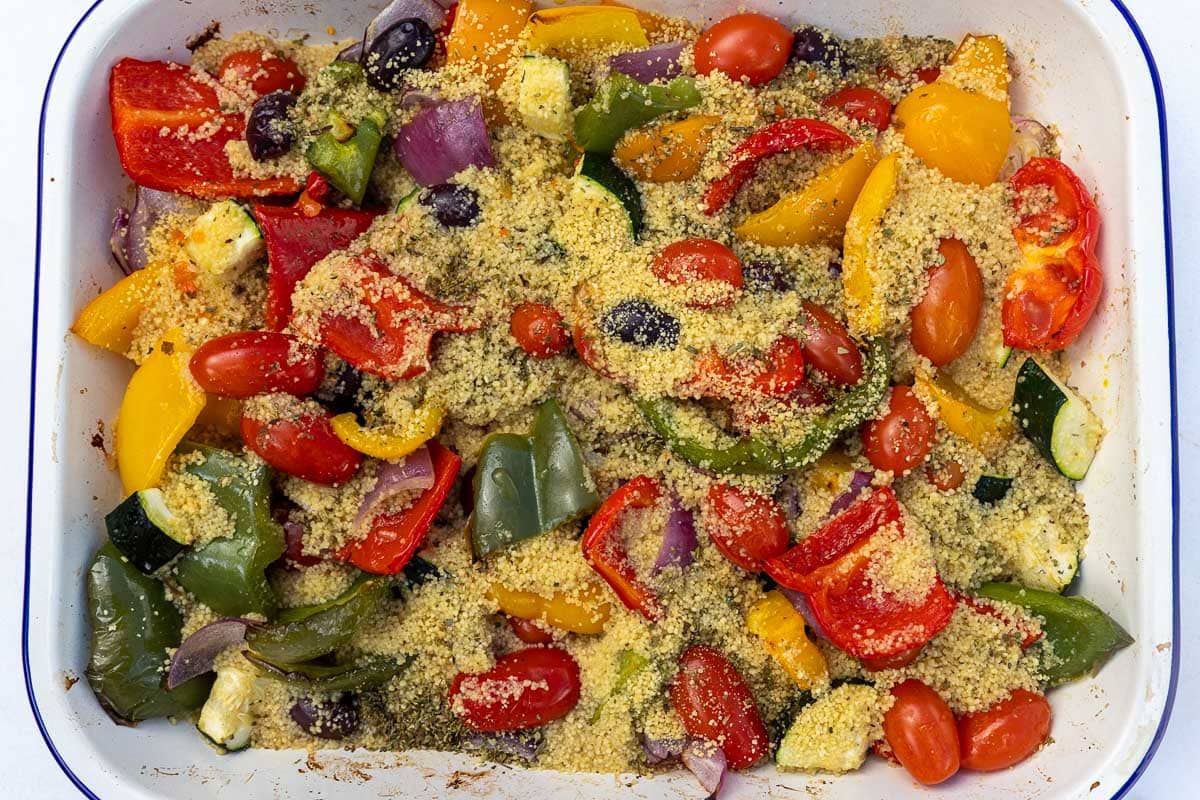 An overhead view of a rectangular baking dish with roasted Mediterranean style vegetables and couscous, just out of the oven.