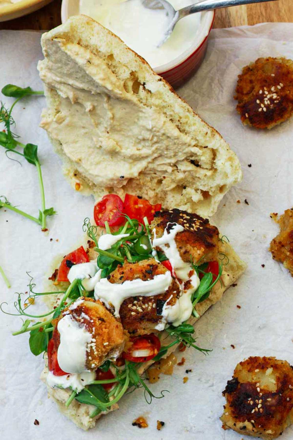 An open sandwich spread with hummus and with sweet potato falafel and salad on.