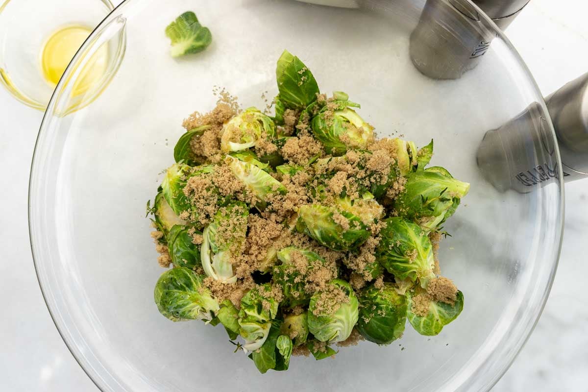 The vegetables in a glass bowl with brown sugar sprinkled over the top.
