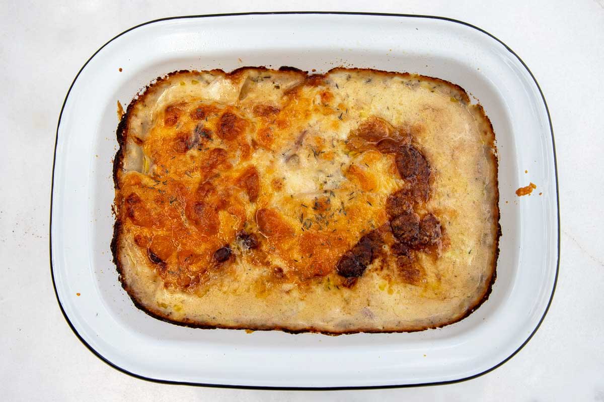 An overhead view of the top of a just-cooked baking dish of potato dauphinoise with bubbly cheese on top.