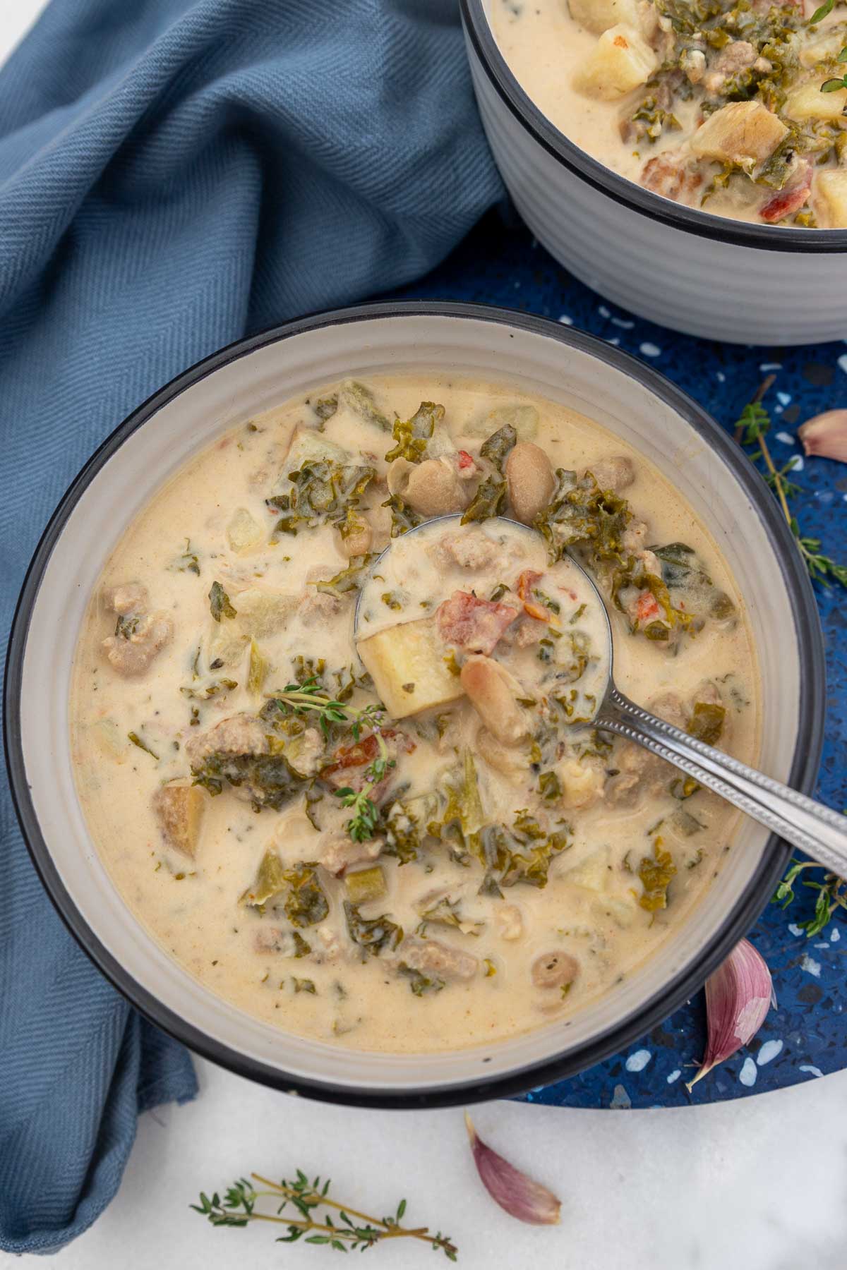 Overhead image of the soup with a spoon in it on a blue and marble background.