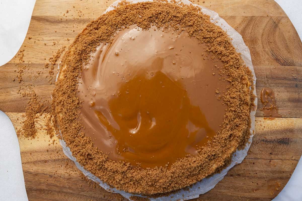 Overhead of the finished and decorated cheesecake on a wooden board.