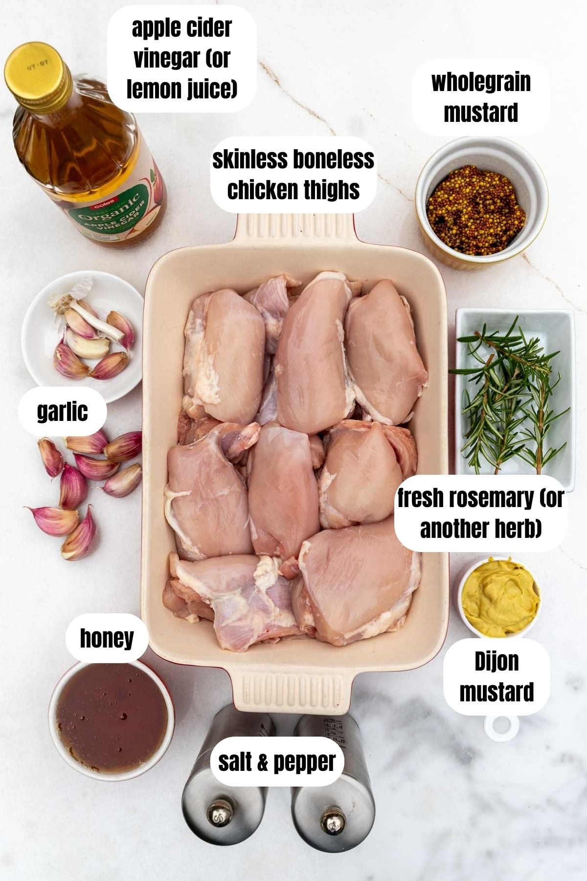 An overhead view of all the ingredients needed for the recipe, labelled, including skinless boneless chicken thighs, honey, salt and pepper, Dijon mustard, wholegrain mustard, salt and pepper, garlic, apple cider vinegar, and fresh rosemary.