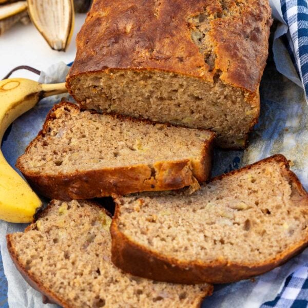 Greek yogurt banana bread from above with 3 slices at the front, on a blue tea towel and board.
