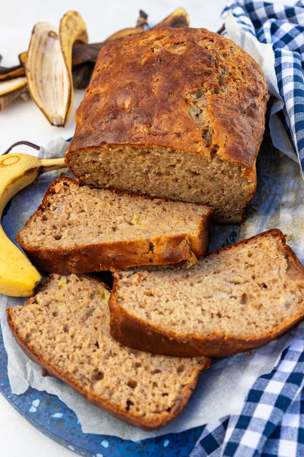 Greek yogurt banana bread from above with 3 slices at the front, on a blue tea towel and board.